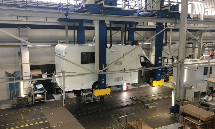 A motorhome being lifted by a hoist in a factory