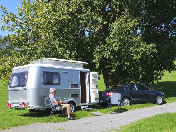 Man sitting on a camping chair in front of the Touring Triton 420 caravan