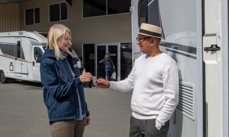 A sales consultant handing over a motorhome key to a new motorhome owner