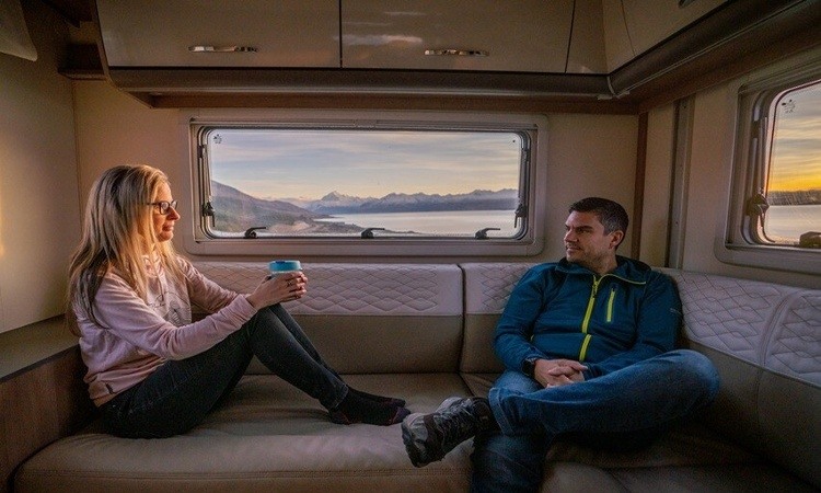 Couple sitting interior rear living area with sunset