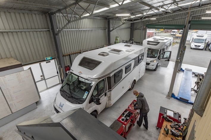 A man doing some maintenance work on a motorhome in a workshop