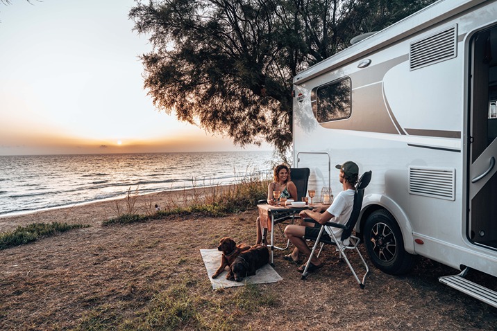A couple with their pet resting outside of their motorhome