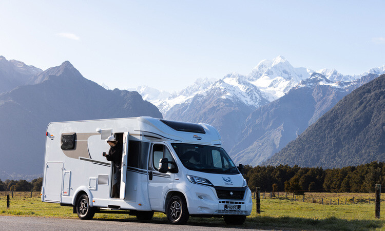 A motorhome out in the outdoor infront of a montain