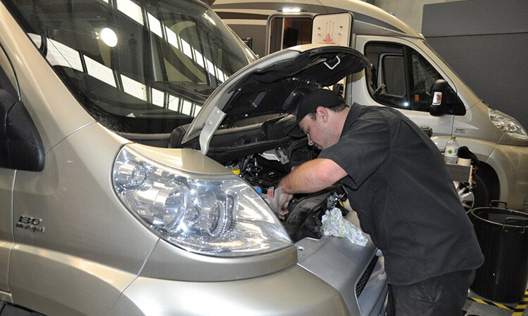 A technician inpecting the engine of a motorhome