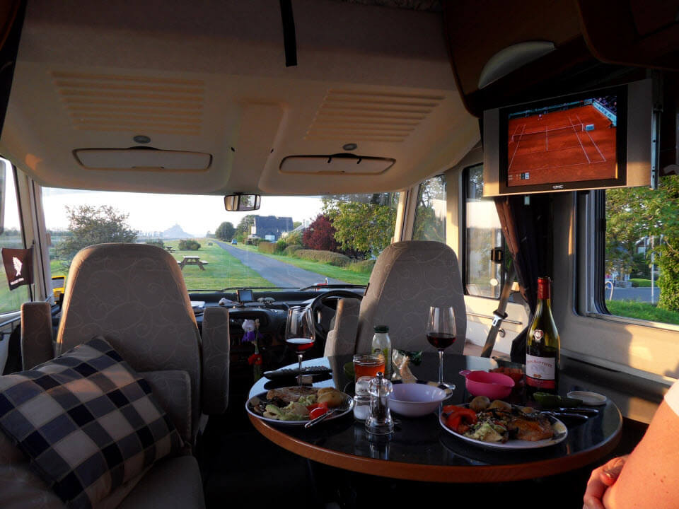 Motorhome dinner set on the table with tennis playing on TV