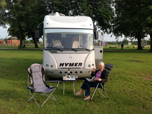 Woman sitting in front of a HYMER motorhome with a glass of wine