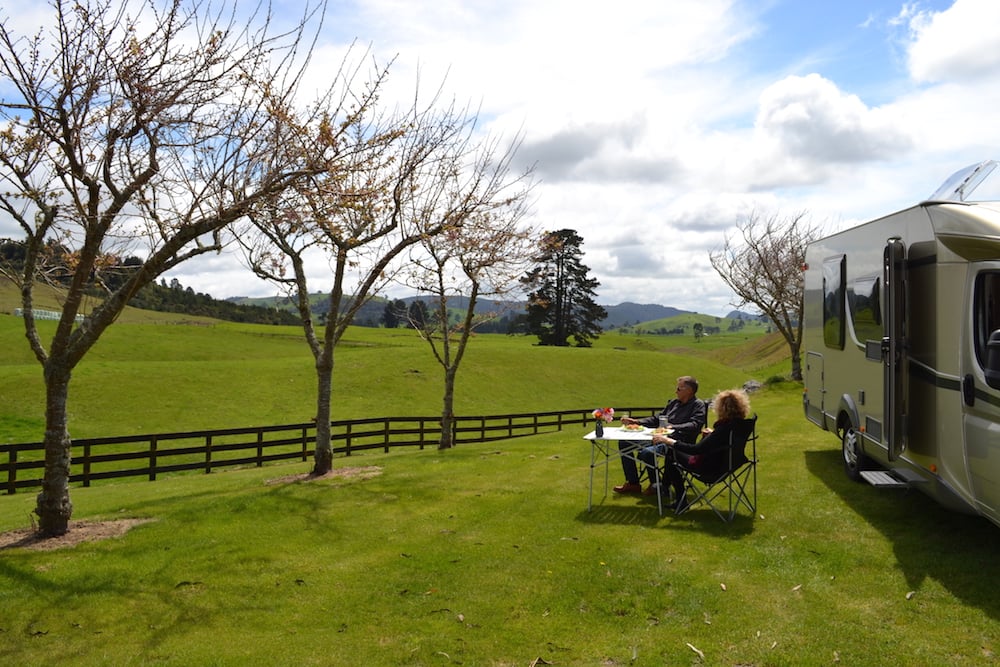 Couple sitting in front of their motorhome enjoying the surrounding scenery